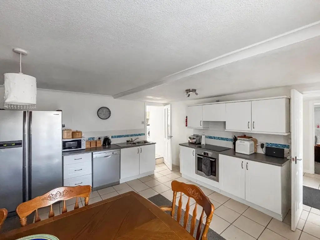 a kitchen with white cabinets and a table and chairs at Ivydene Cottage in Cromarty