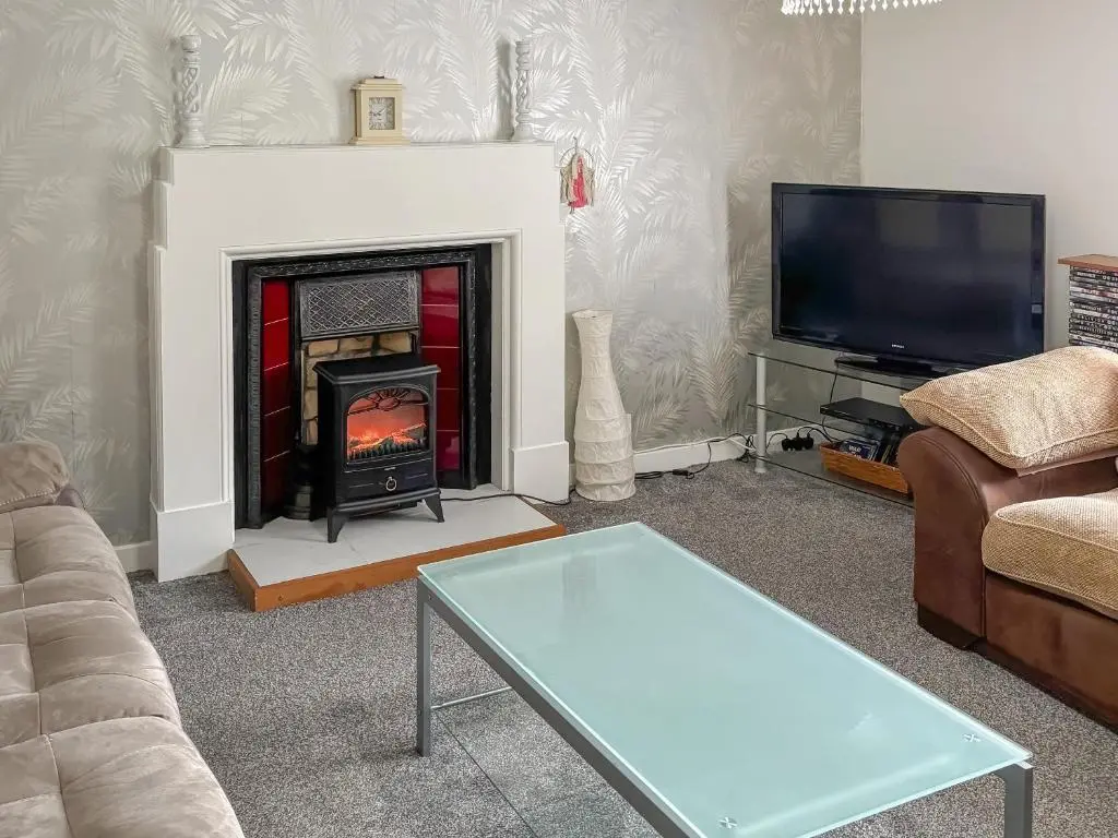 a living room with a fireplace and a tv at Ivydene Cottage in Cromarty