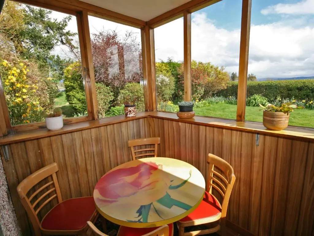 a porch with a table and chairs and a window at Old Post Office House in Knockbain