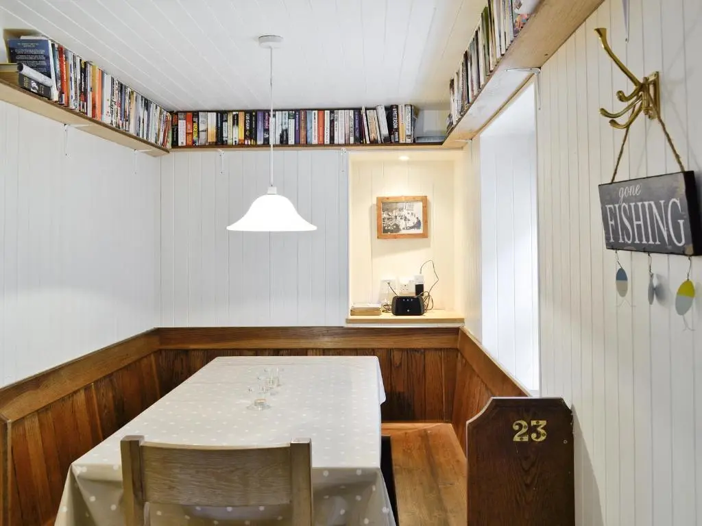 a dining room with a table and some books at Crovie Cottage in Gardenstown