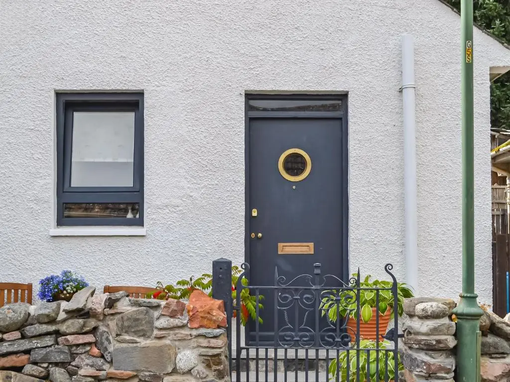 a blue door on a white house with a window at Douneside Cottage in Inverness