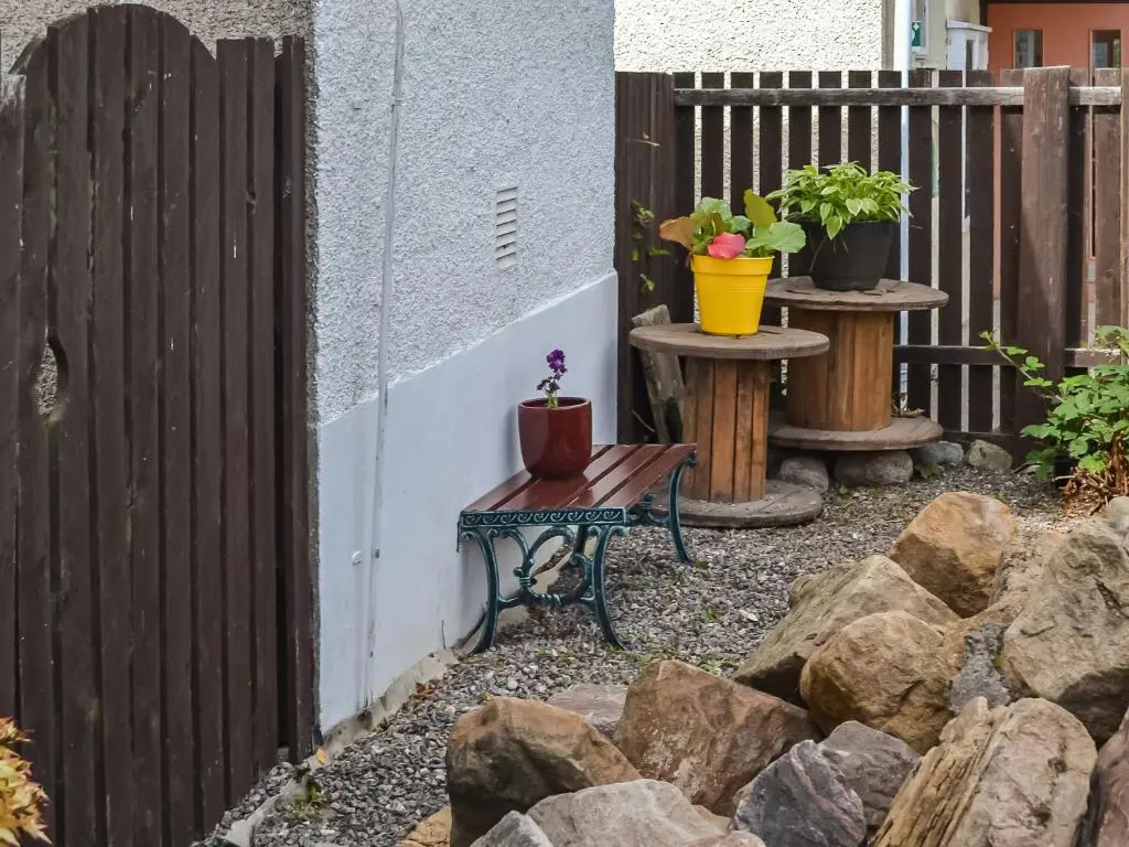 a bench with two potted plants on it next to a fence at Douneside Cottage in Inverness