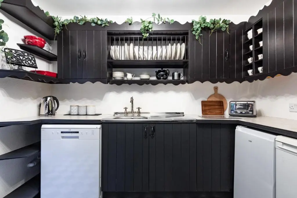 a kitchen with black cabinets and white appliances at Criss Cross Cottage in Inverness