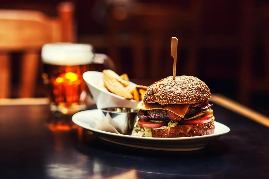 a sandwich and fries on a table with a glass of beer at Corriegarth Hotel in Inverness