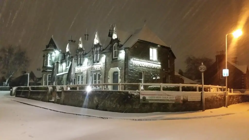 a large house in the snow at night at Corriegarth Hotel in Inverness