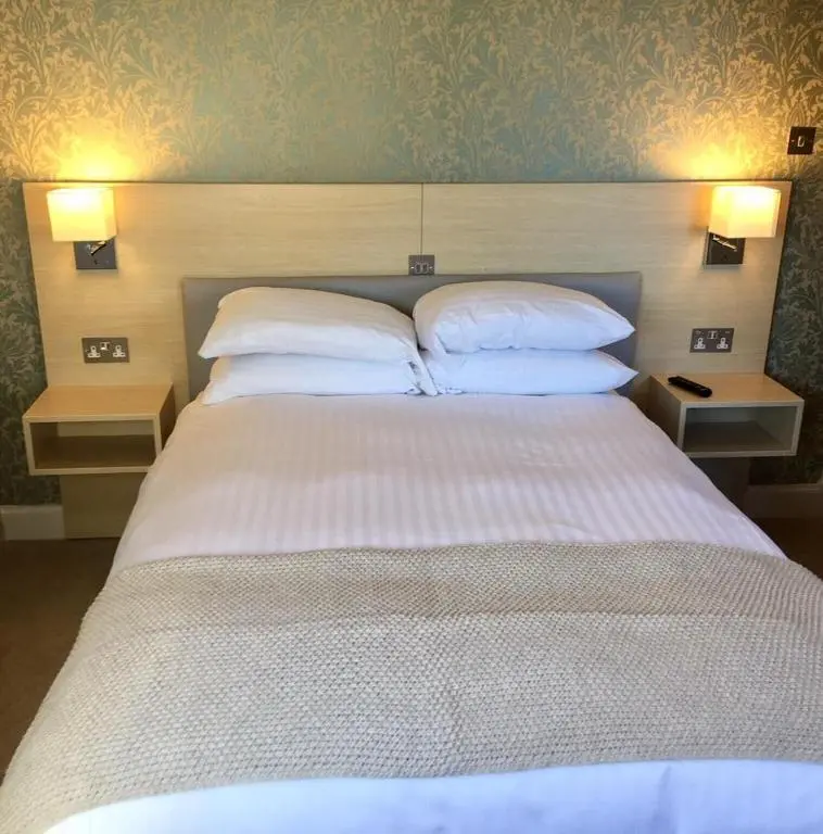 a bedroom with a large bed with two pillows at Corriegarth Hotel in Inverness