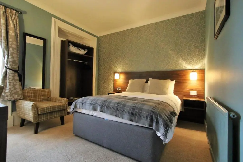 a bedroom with a bed and a chair at Corriegarth Hotel in Inverness
