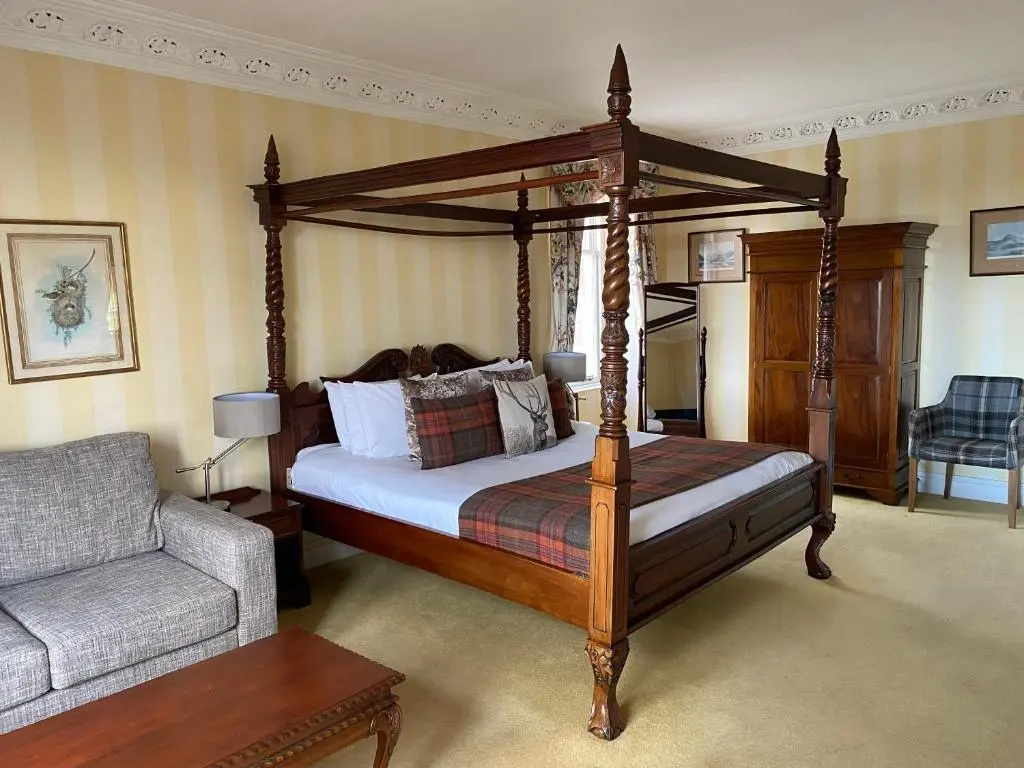 a bedroom with a canopy bed and a chair at Boat Country Inn and Restaurant in Boat of Garten
