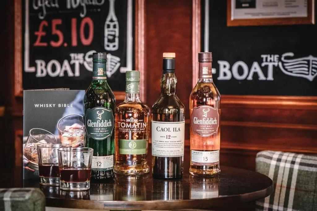 a group of bottles of whiskey and glasses on a table at Boat Country Inn and Restaurant in Boat of Garten
