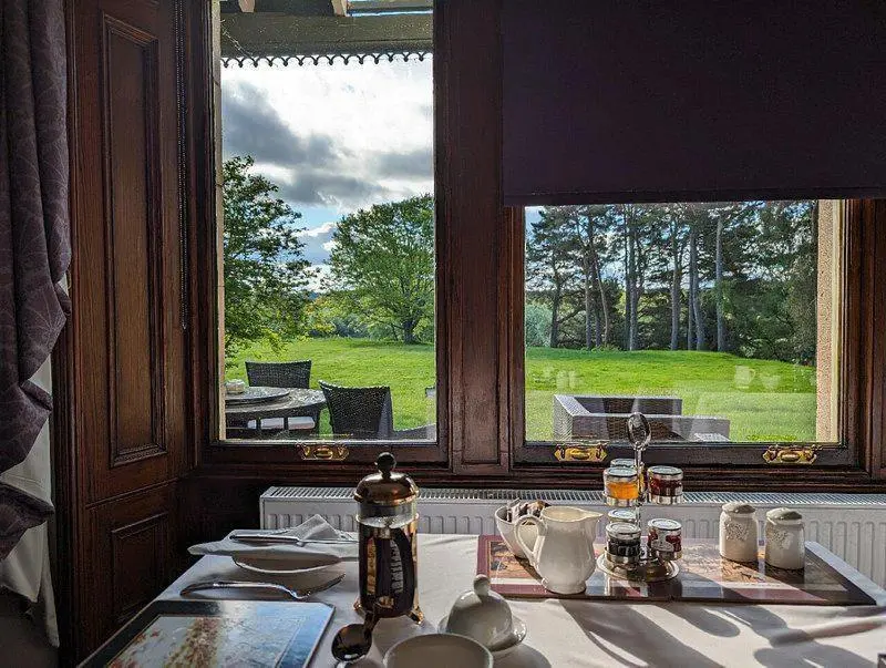 a kitchen with a table with a view of a garden at Dalrachney Lodge in Carrbridge