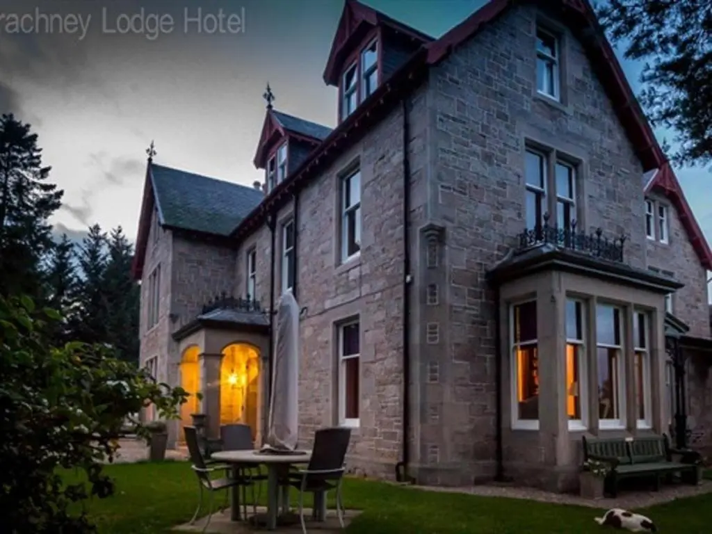 a large brick house with a table in front of it at Dalrachney Lodge in Carrbridge