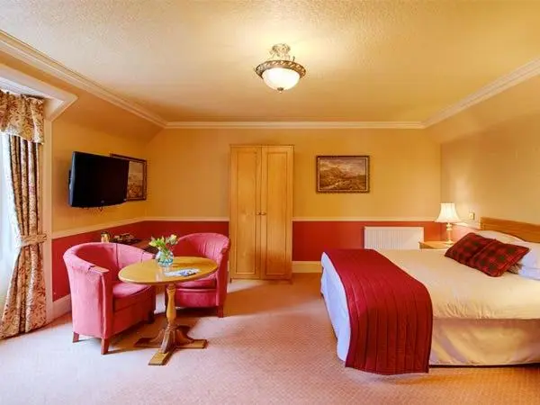a hotel room with a bed and a table and chairs at Kincraig Castle Hotel in Invergordon