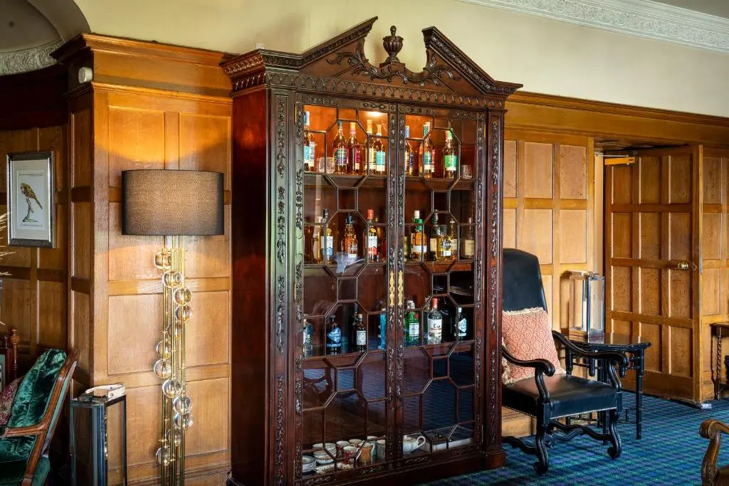 a large wooden cabinet with bottles in it in a room at Kincraig Castle Hotel in Invergordon