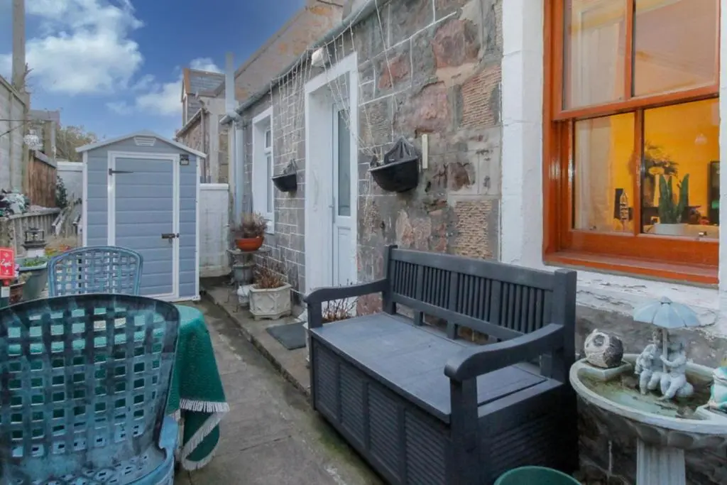 a bench sitting on the side of a building at 2 Bed Cottage Sleeps 4-Pets Welcome-Private Garden in Buckie