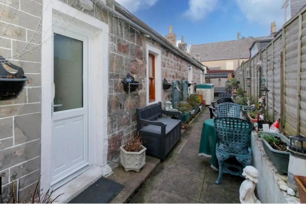 an alley with a door and chairs and plants at 2 Bed Cottage Sleeps 4-Pets Welcome-Private Garden in Buckie