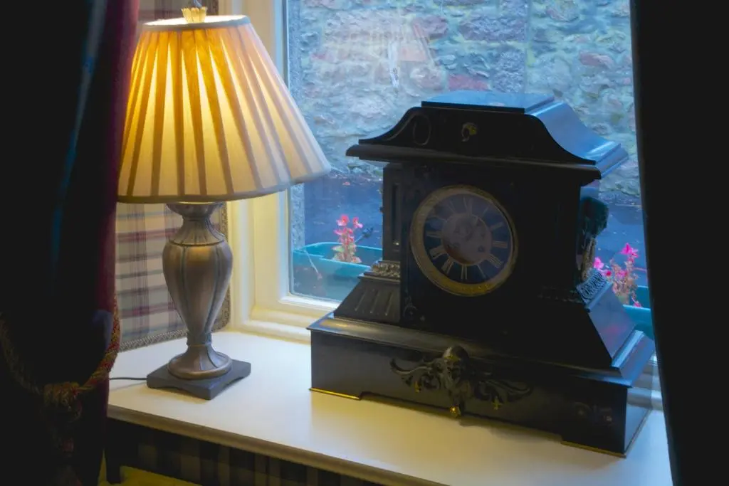 a lamp and a clock on a table next to a window at Loch Kinord Hotel in Dinnet