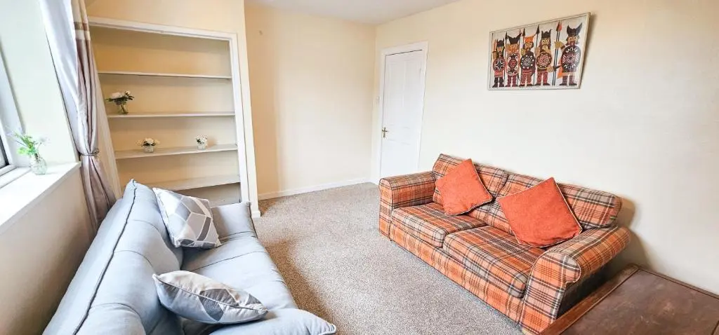 a living room with a couch with orange pillows at 1 Bedroom House - Inverness - River Canal in Inverness