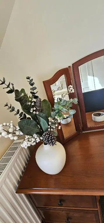 a white vase with flowers on a wooden table at Balmore Farmhouse near Lochness in Inverness