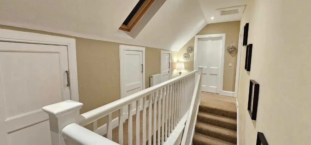 a white staircase in a home with white railings at Balmore Farmhouse near Lochness in Inverness