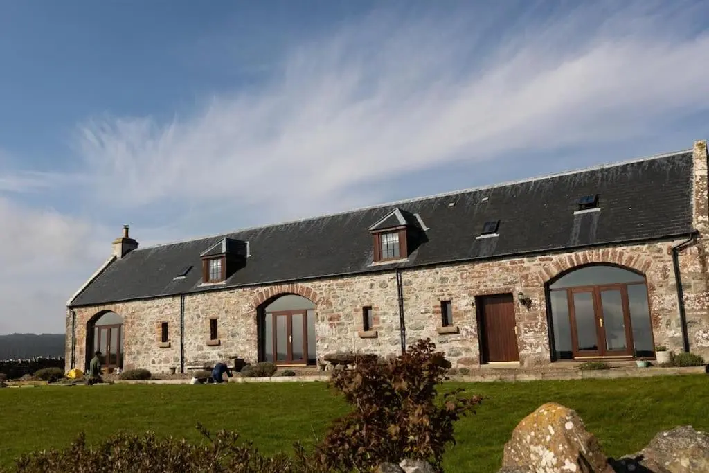 a stone house with a black roof at Balvraid Steading - Awesome views, near Dornoch in Dornoch