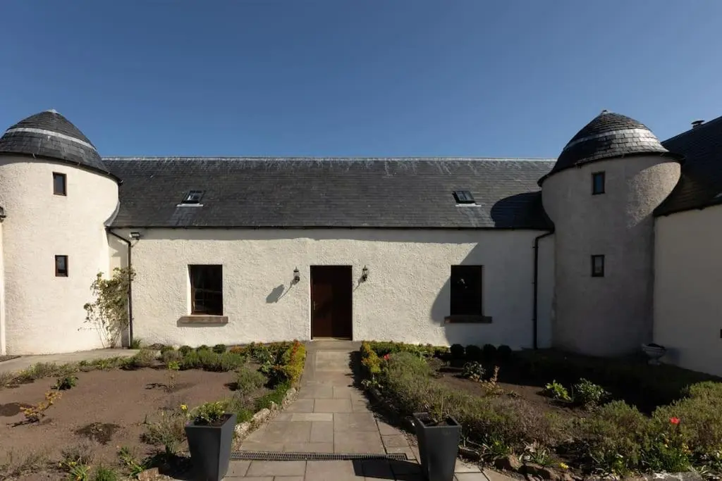 a white building with a black roof and a driveway at Balvraid Steading - Awesome views, near Dornoch in Dornoch