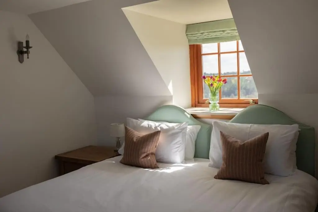 a bedroom with a white bed with pillows and a window at Balvraid Steading - Awesome views, near Dornoch in Dornoch