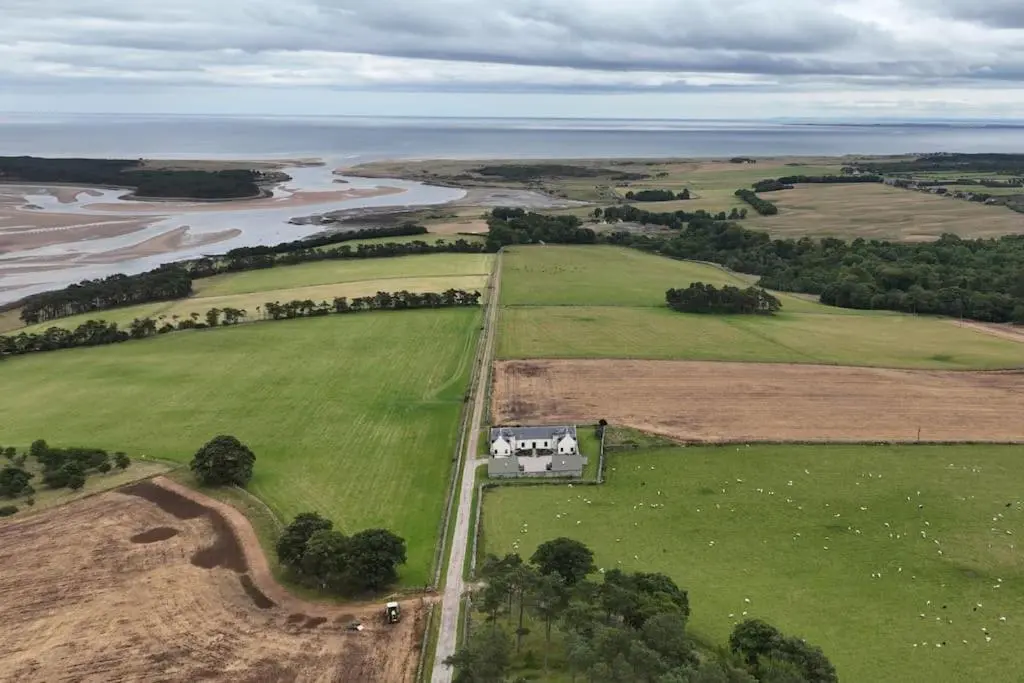an aerial view of a house in a field next to a river at Balvraid Steading - Awesome views, near Dornoch in Dornoch
