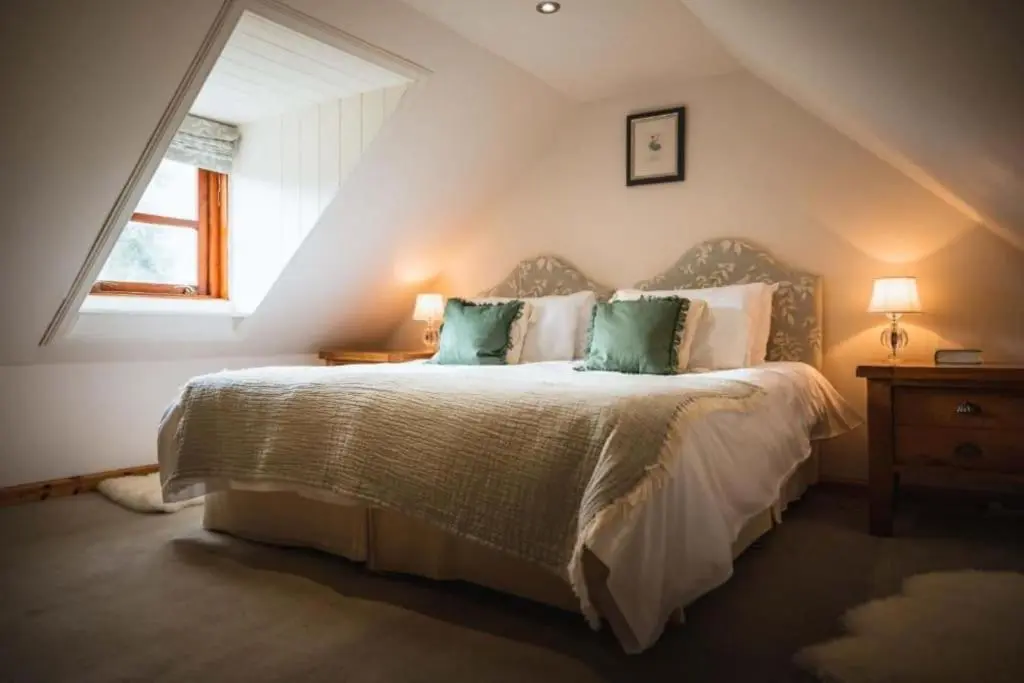 a bedroom with a bed with green pillows and a window at Grieves Cottage, near Dornoch in Dornoch