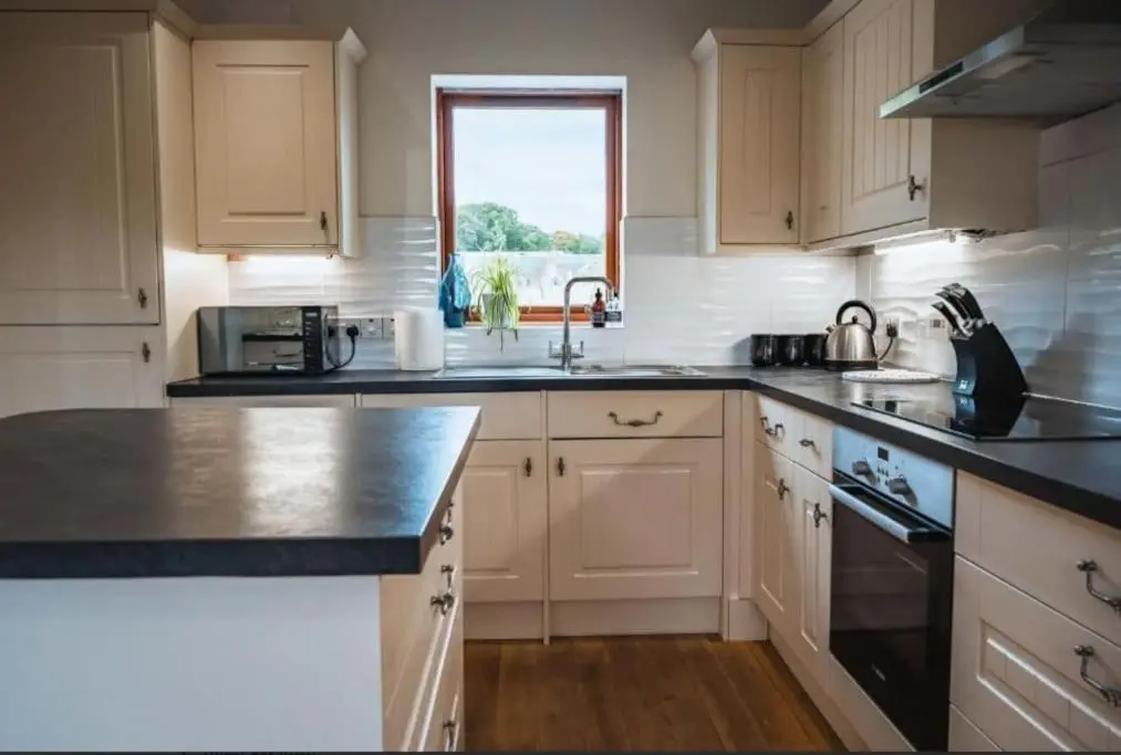 a kitchen with white cabinets and a black counter top at Grieves Cottage, near Dornoch in Dornoch