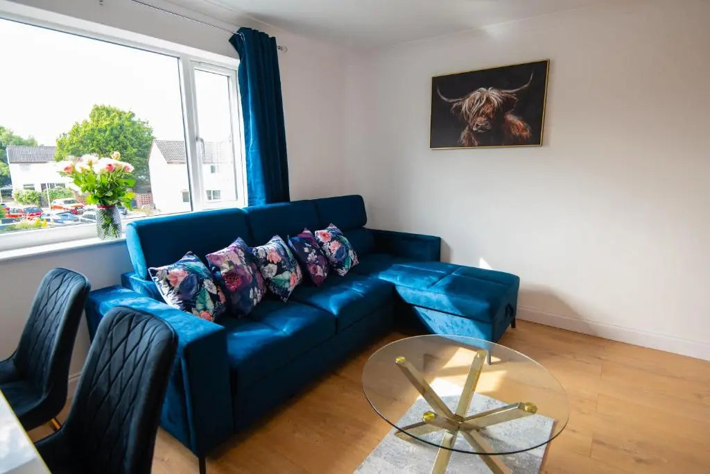 a blue couch in a living room with a window at Two Bedroom Hilton Apartment 1st floor in Inverness