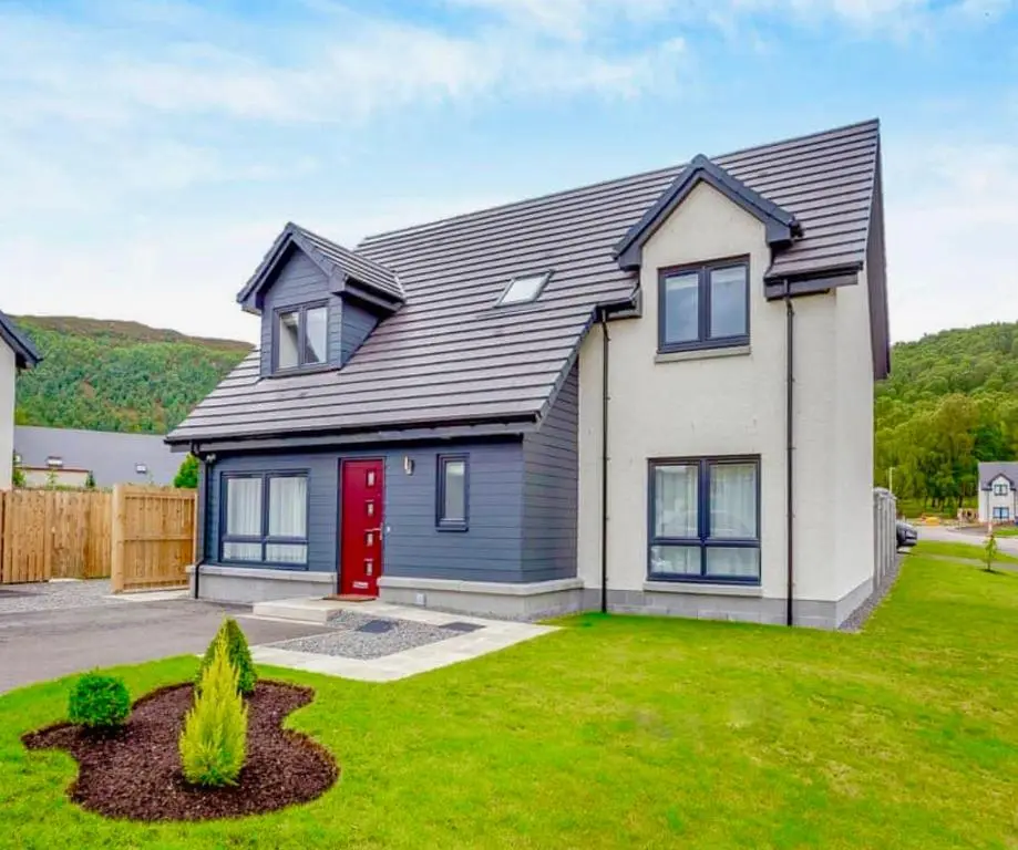 a house with a red door in a yard at The Beech House in Aviemore