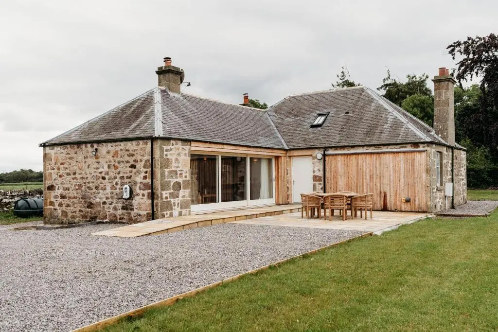 a stone house with a table and chairs in front of it at No1 Burgie Mains Cottage in Forres