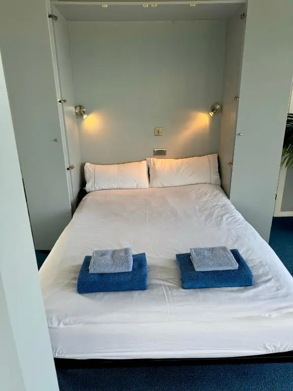 a white bed with two blue towels on it at The Lighthouse in Nairn