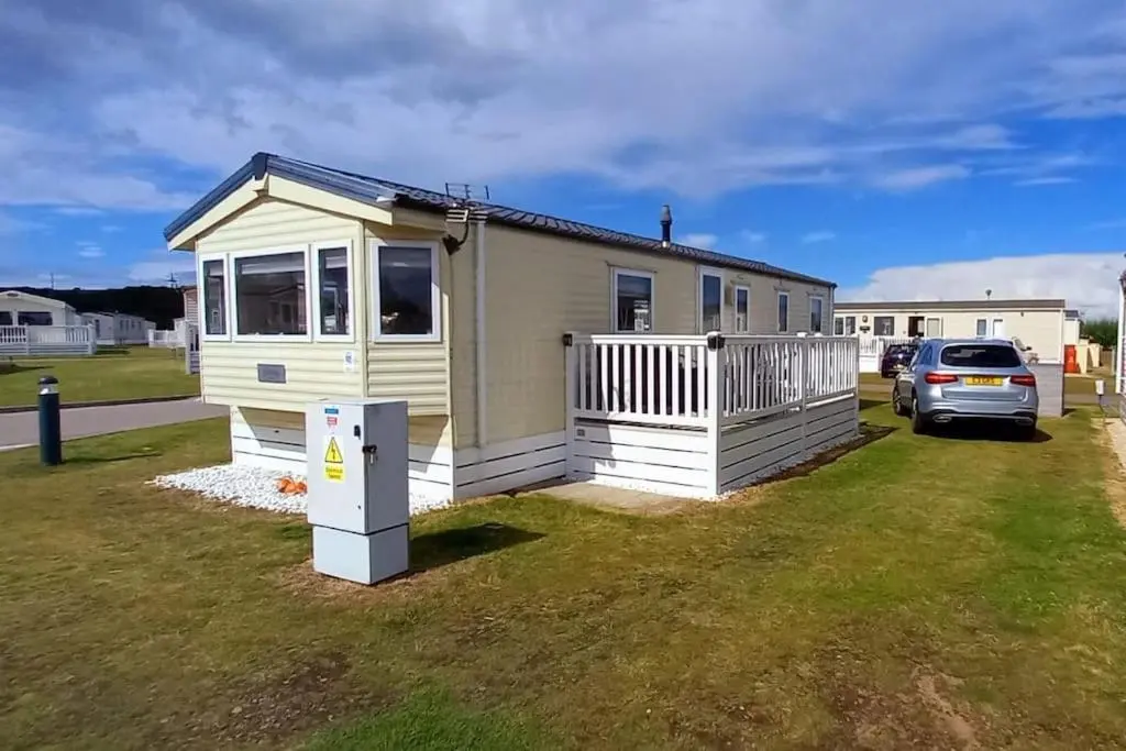 a tiny house with a car parked in a yard at Coral Cove in Lossiemouth