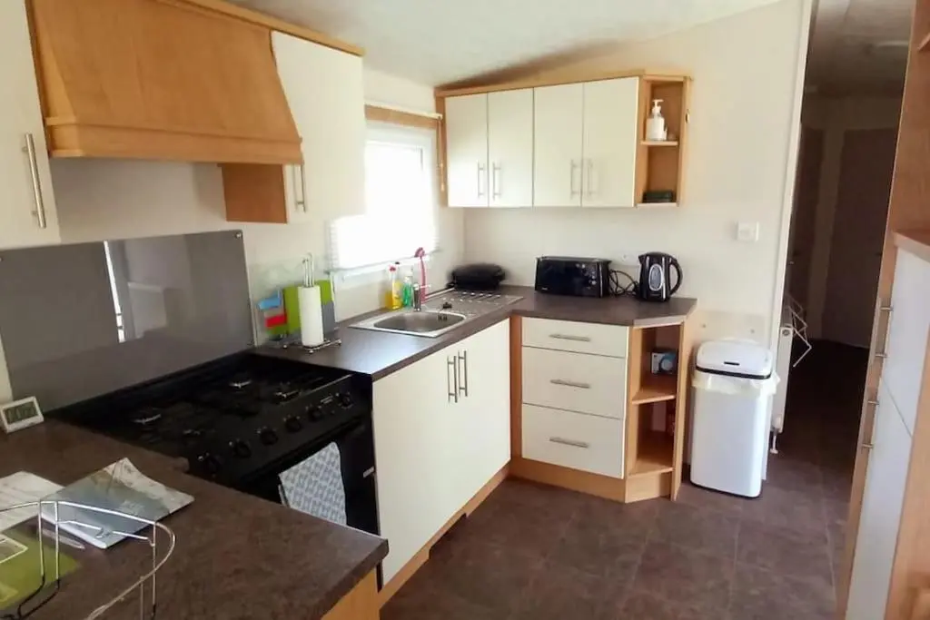 a small kitchen with white cabinets and a stove at Coral Cove in Lossiemouth