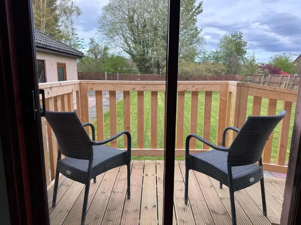 two chairs sitting on a deck next to a window at Oaklyn,Highland Village of Beauly, Quiet Neighbourhood, One Bed, Min 5 nights in Beauly