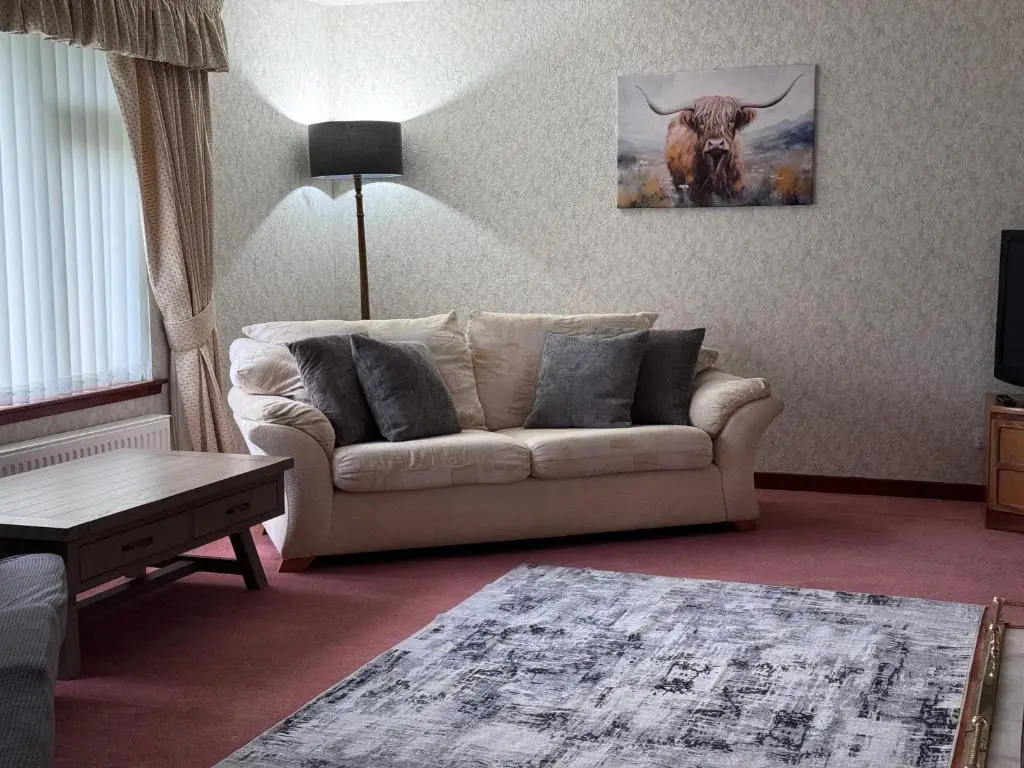 a living room with a couch and a picture of a bull at Oaklyn,Highland Village of Beauly, Quiet Neighbourhood, One Bed, Min 5 nights in Beauly