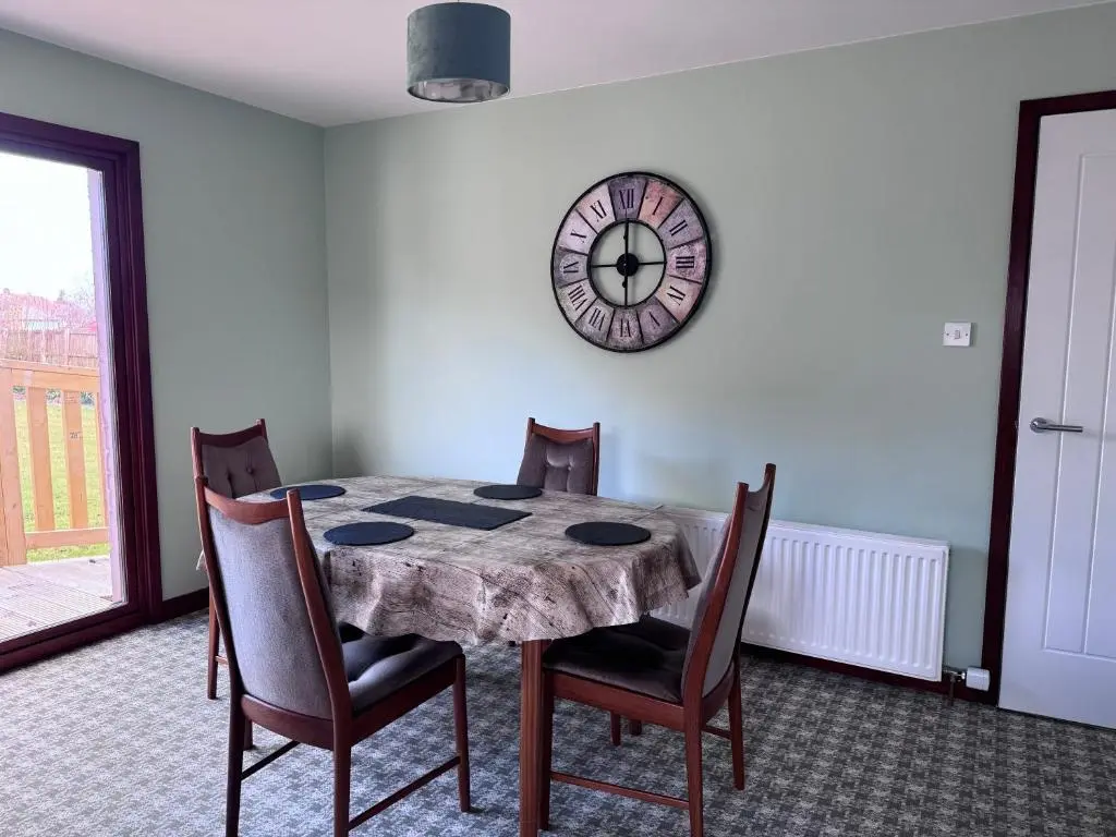 a dining room table with chairs and a clock on the wall at Oaklyn,Highland Village of Beauly, Quiet Neighbourhood, One Bed, Min 5 nights in Beauly