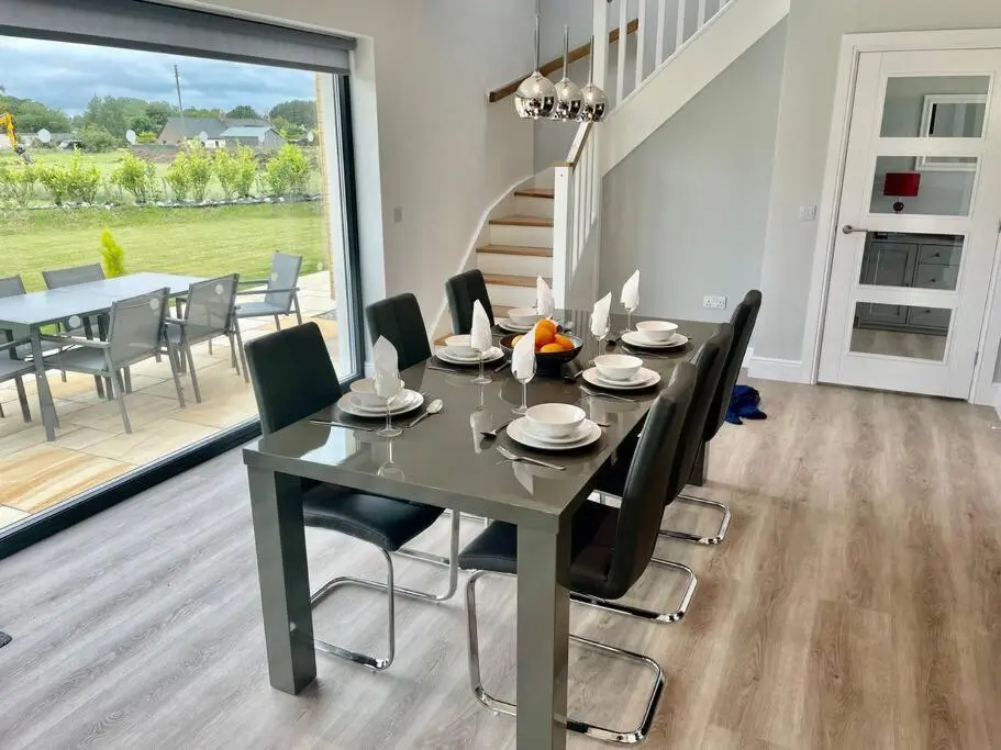 a dining room with a table and chairs and a large window at Ash Mill - Dornoch in Dornoch