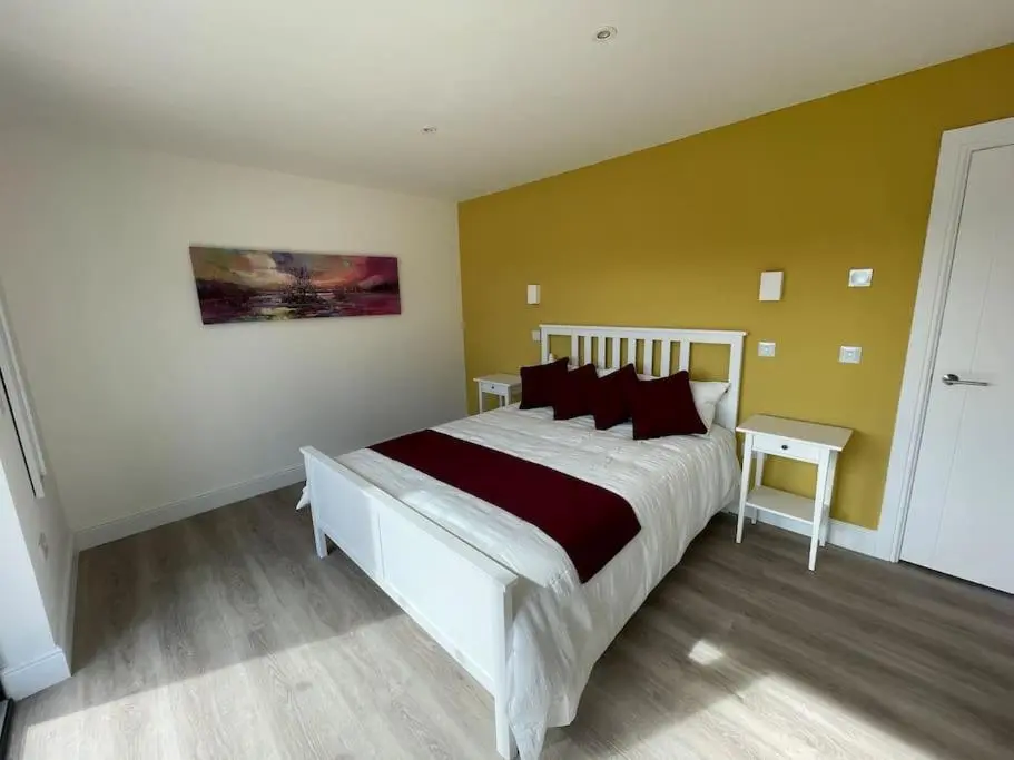a bedroom with a large white bed with red pillows at Ash Mill - Dornoch in Dornoch