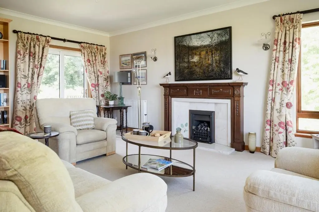 a living room with a fireplace and a table at Fairways - Seasgair Lodges in Nairn