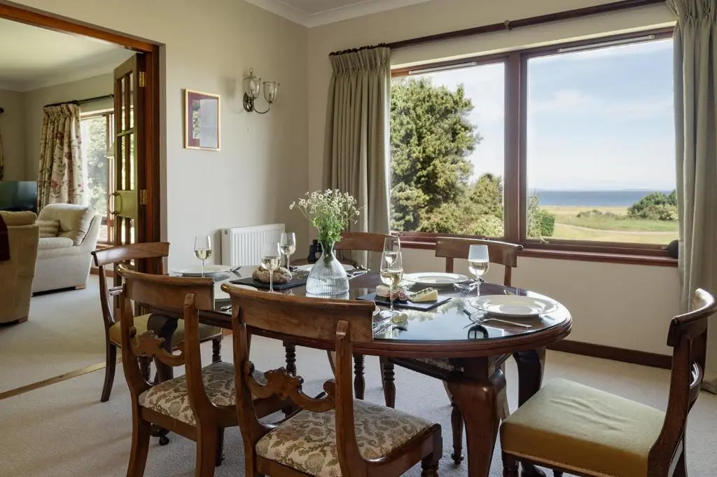 a dining room with a table and a large window at Fairways - Seasgair Lodges in Nairn