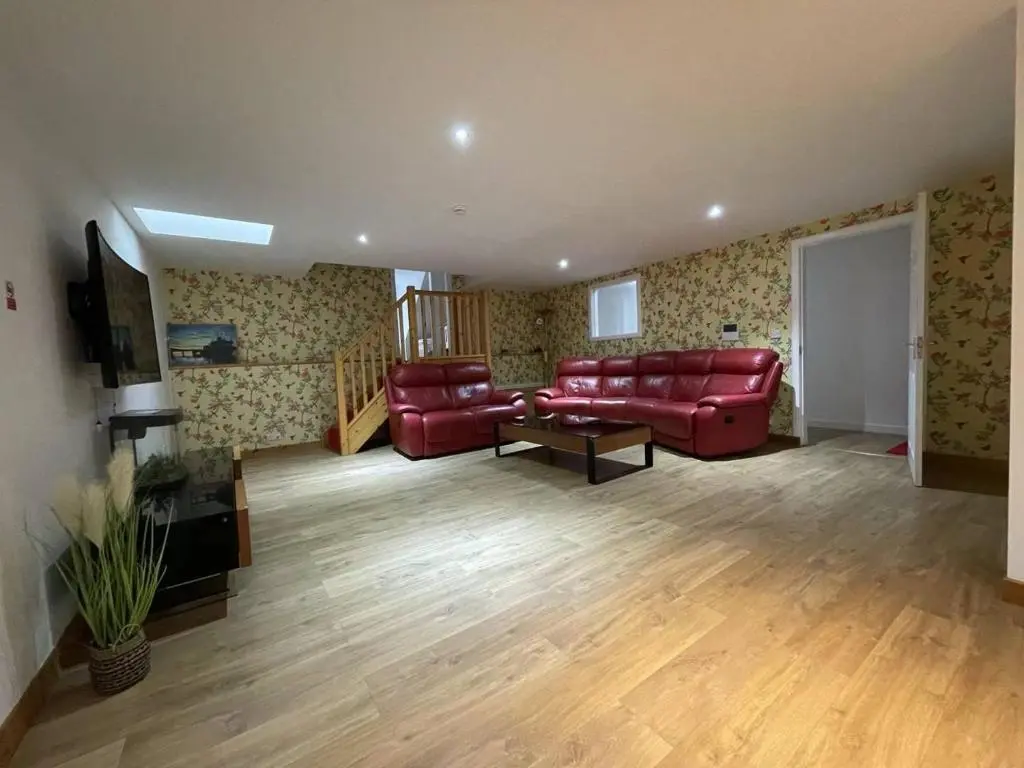 a living room with red leather furniture and wooden floors at Sunshine three bedrooms Apartment in Insch