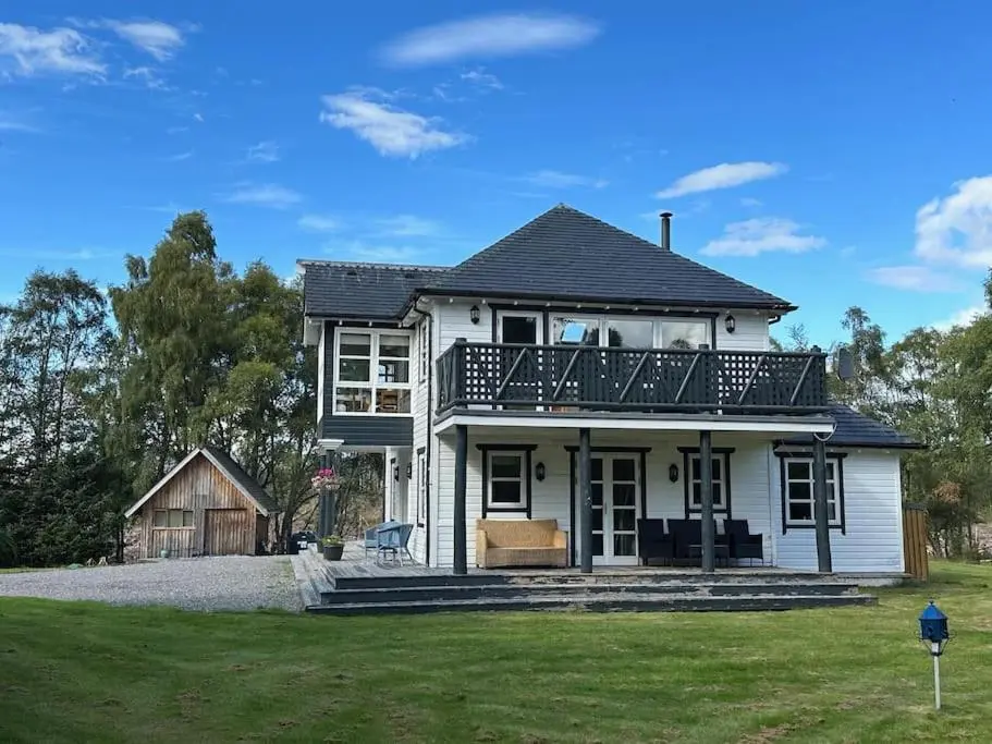 a white house with a balcony on top of it at Heath House Loch Ness in Errogie
