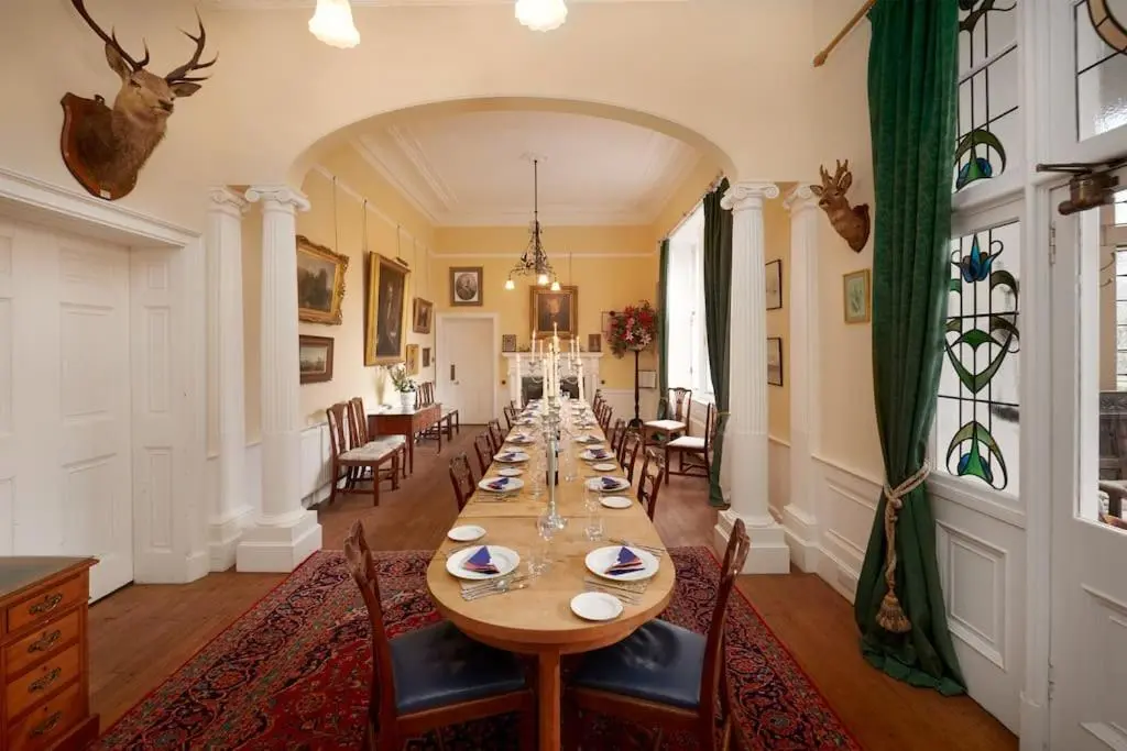 a long dining room with a long table and chairs at Idyllic 12 bedroom Country Home in Forres