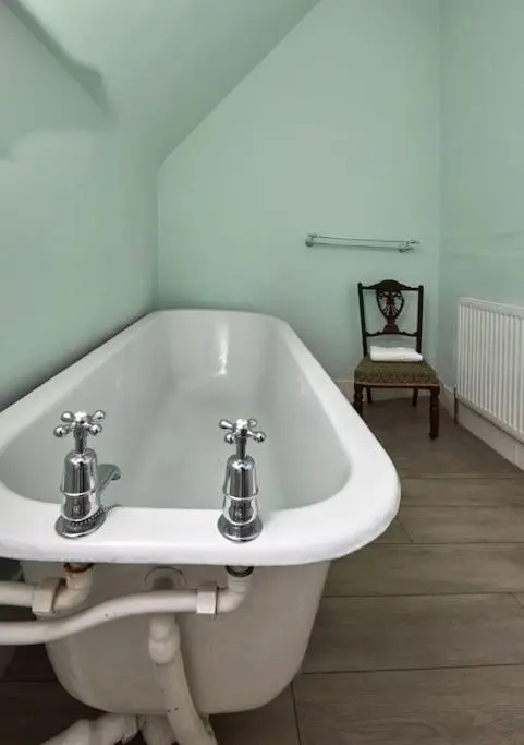 a white bath tub with two faucets in a bathroom at Idyllic 12 bedroom Country Home in Forres