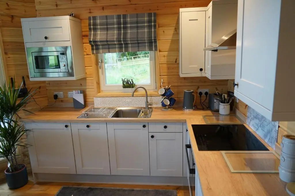 a kitchen with white cabinets and a sink and a window at Cherry Tree Lodge in Inverness