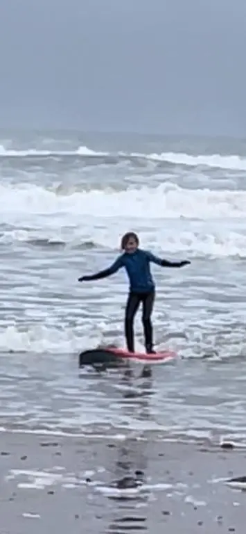 a person standing on a surfboard in the ocean at Cobblehouse Country Cabins no TRADE WORKERS in Inverkeithny