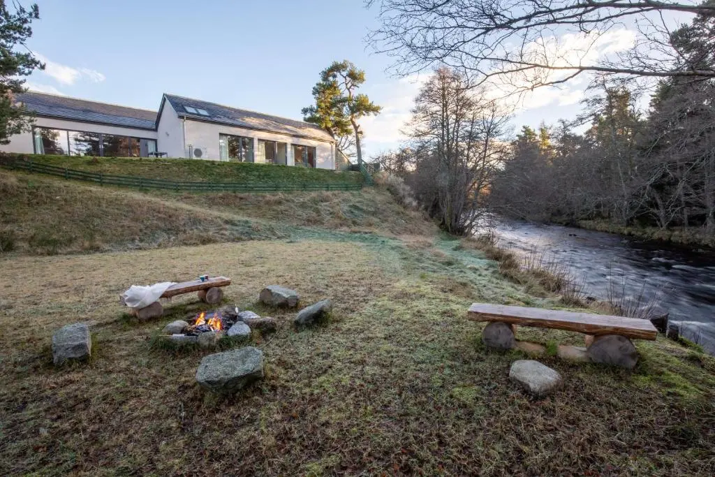 a fire pit on a hill next to a house at Riverside Lodge - Seasgair Lodges in Nethy Bridge