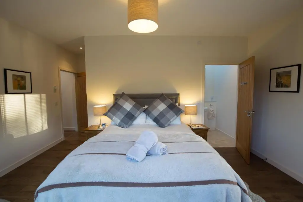 a bedroom with a large bed with two towels on it at Riverside Lodge - Seasgair Lodges in Nethy Bridge